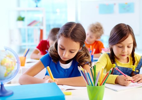 Photo image of children sitting at their school desk writing in a jotter (Shutterstock image)