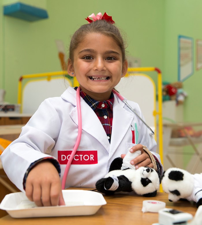 Photo image of a child dressed up as a doctor playing with toy panda's (Glasgow Children's Hospital Charity Image)