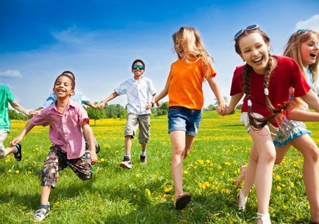 Photo image of children outside holding hands running on grass (Shutterstock image)