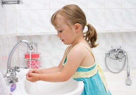 Photo image of a child washing their hands in a bathroom (Shutterstock image)