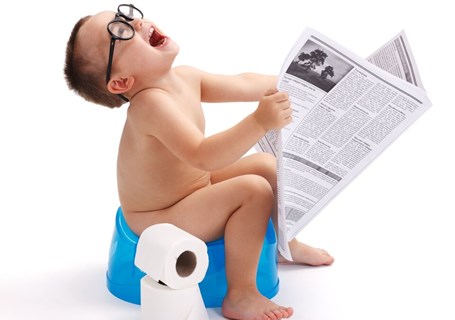 Photo image of a child sitting on a potty reading a newspaper (Shutterstock image)
