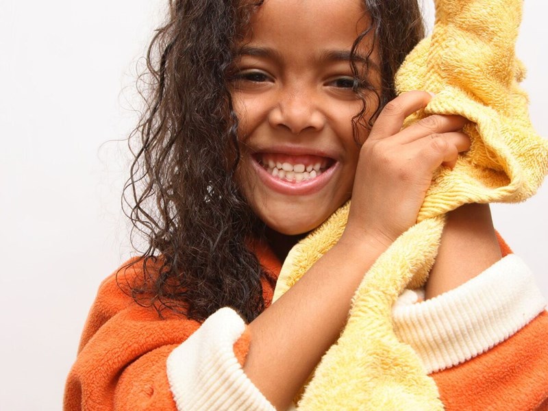 Photo image of a child wearing a dressing gown and drying their hair with a towel (shutterstock image)