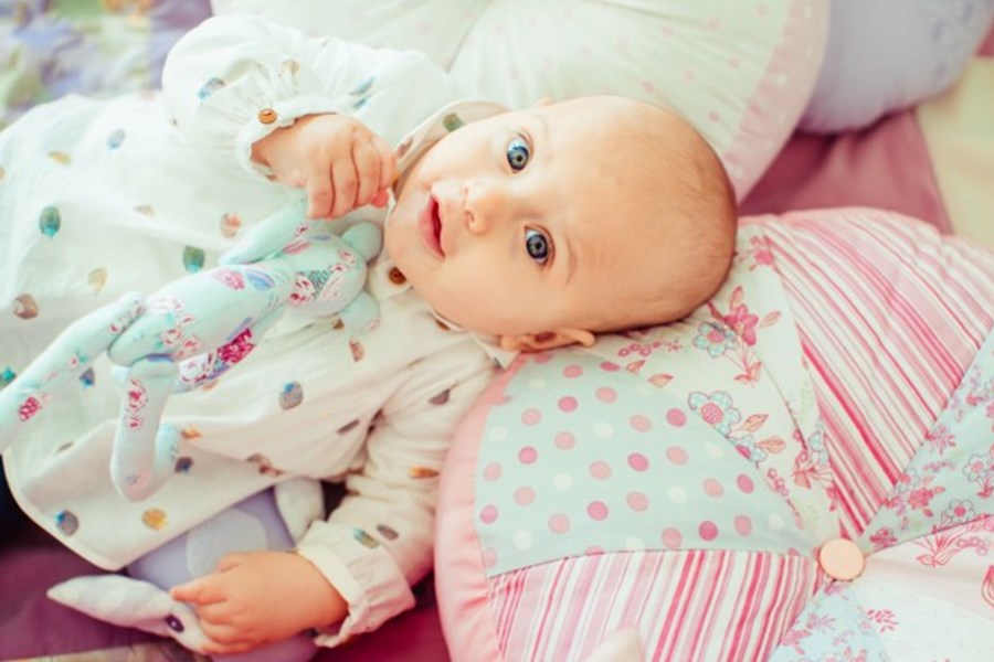 Photo image of a baby lying on a pillow looking directly into the camera (Freepik image)