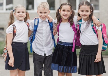 Photo image of four primary school children standing outside looking directly into the camera (Freepik image)