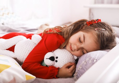 Graphic image of a child sleeping on a bed cuddling a teddy bear (Freepik image)