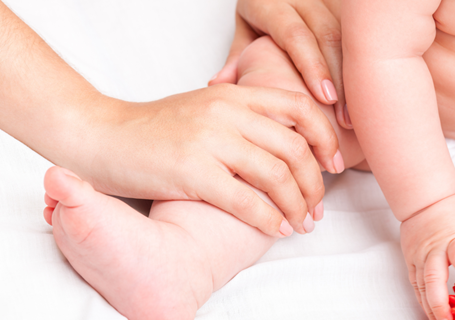 Photo image of an adult massaging a baby's leg (Canva image)