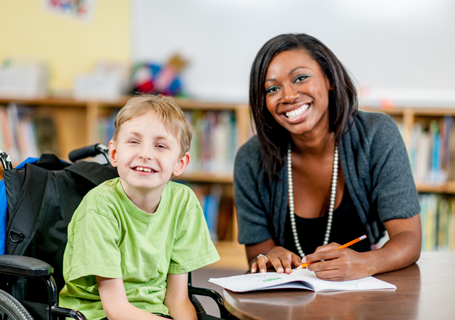 Photo image of a child sitting in a wheelchair working with an adult in a school setting (Canva image)