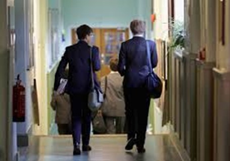 Photo image of two teenagers walking down a school corridor