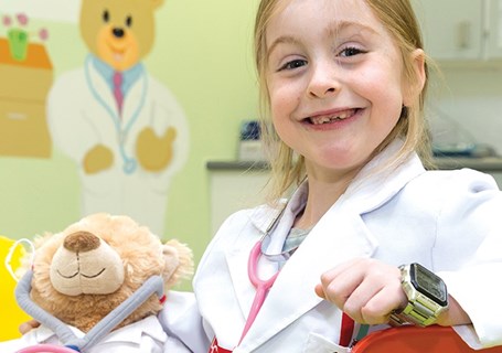 Photo image of a child dressed up as a doctor and holding a teddy bear who is also dressed up as a doctor (Glasgow Children's Hospital Charity Image)