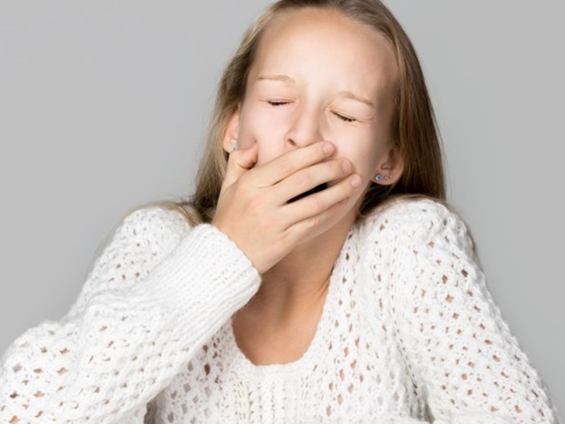 Photo image of a teenager putting their hand over their mouth during a yawn (Freepik image)